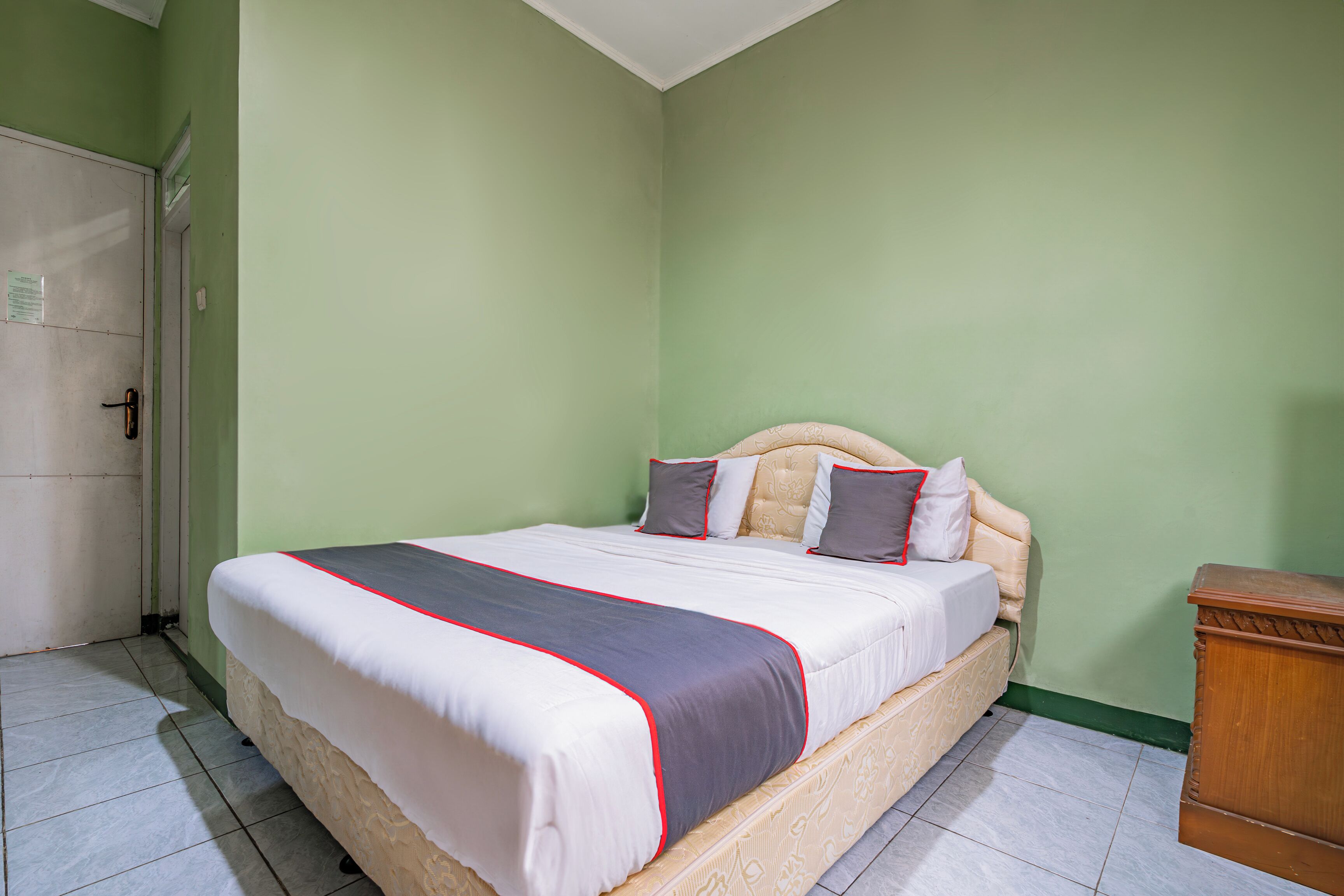 A neatly made bed with a white and grey bedspread, a wooden headboard, and two pillows.