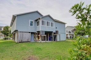 Une maison à deux étages avec un porche à l’avant, un garage et un petit jardin à l’arrière.