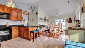 A spacious kitchen with wooden cabinets, a black stove, and a bar area with stools. - Seaing is Believing | Surf City, NC | 4 Bedrooms | Short Walk to Beach (Surf City)