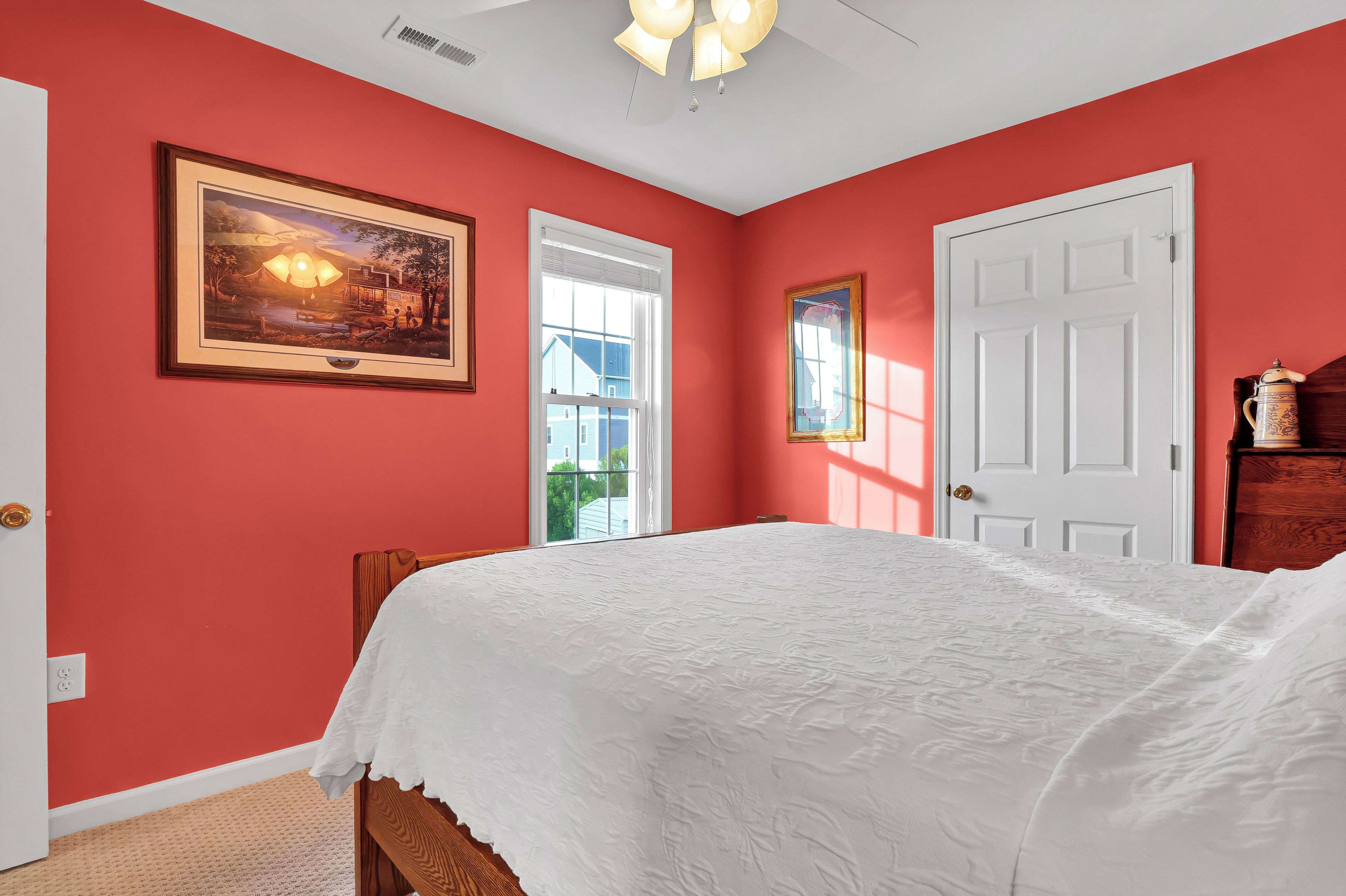 Une chambre à coucher avec un grand lit, un tableau encadré au mur et une porte avec une fenêtre.