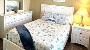 A bedroom with a bed, nightstands, a lamp, a mirror, and a framed picture on the wall. - 2 bathroom 1 bath Cottage (Rockport)