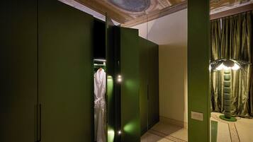 Een hotelkamer met groene wanden, een badjas hangend aan een rek en een kroonluchter.