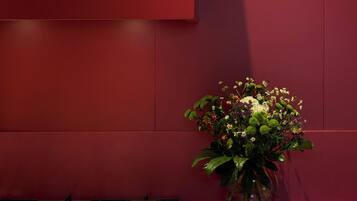 Une cuisine avec un mur rouge, une cuisinière à gaz et un vase rempli de fleurs posé sur le comptoir.