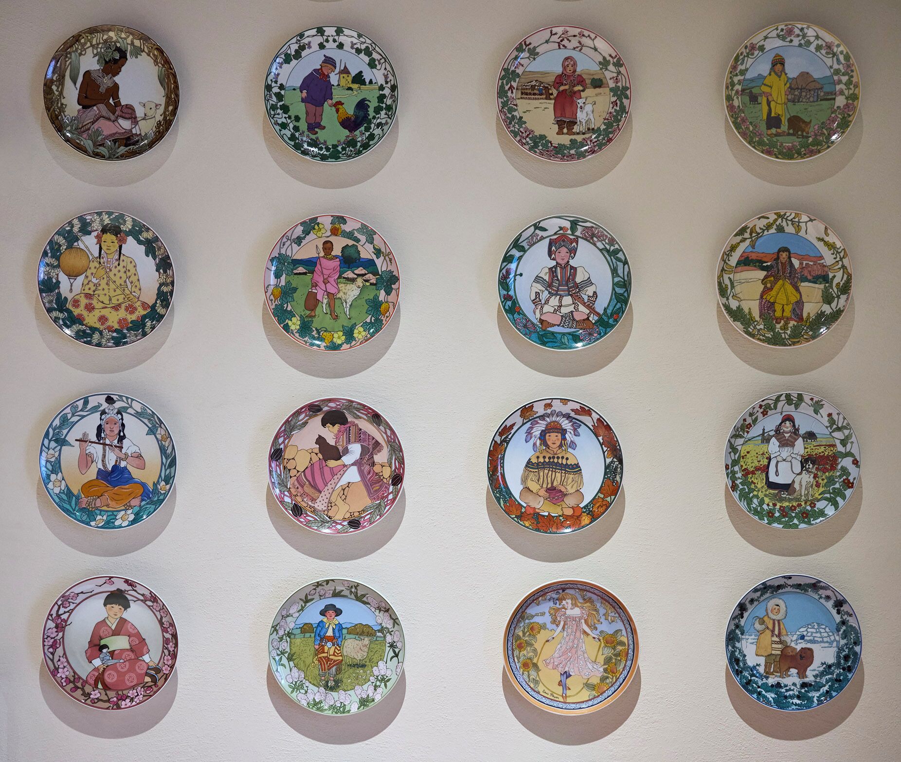 Una pared con varios platos circulares, cada uno con escenas de diferentes culturas.