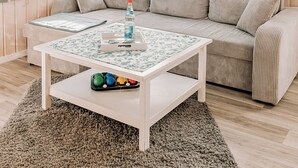 A cozy living room with a sofa, a coffee table, and a rug. - Waldhaus 2 mit Whirlpool - Ferienhäuser Insel Usedom - Direkt am Achterwasser! (Lütow)