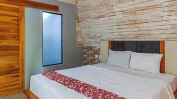 Un dormitorio con cabecera de madera, un ventanal grande y una cama con ropa de cama blanca y una manta roja y blanca estampada.