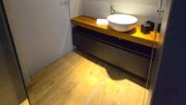 Un baño pequeño y moderno con tocador de madera, un lavabo blanco y un espejo encima.