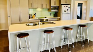 A kitchen with a central island, bar stools, stainless steel appliances, and beige cabinetry. - Guichen Villa 3 - Wi-Fi, Pets welcome outside (Robe)