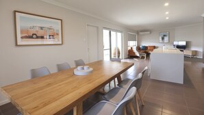 A dining area with a wooden table and chairs, a kitchen area with a TV, and a framed picture on the wall. - Guichen Villa 3 - Wi-Fi, Pets welcome outside (Robe)