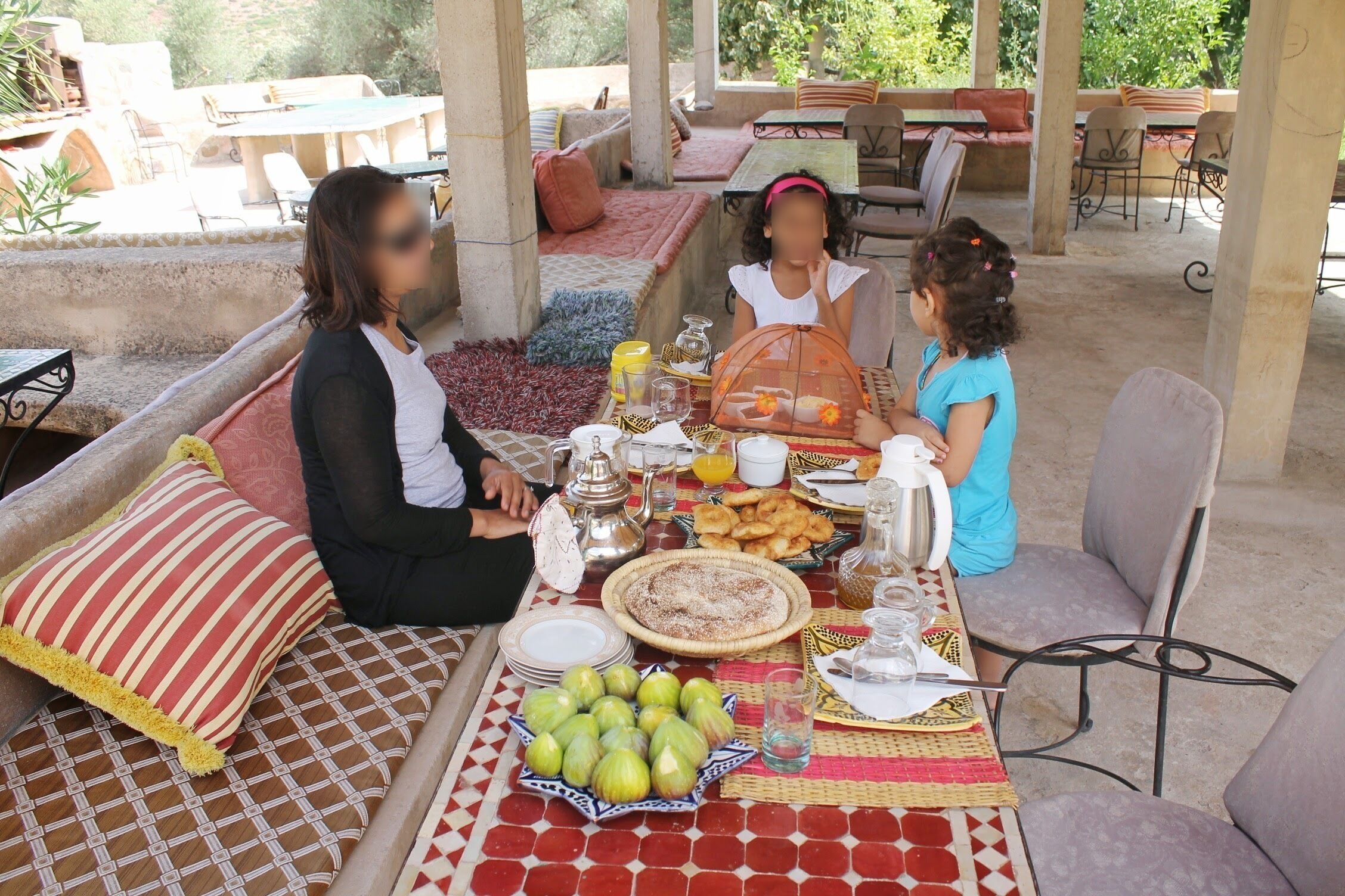 A covered outdoor dining area with a table set for a meal, featuring a variety of dishes and a decorative centerpiece.