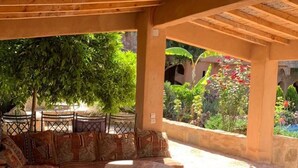 A covered outdoor seating area with a sofa and a round table, surrounded by patterned rugs and cushions. - Azzaouia Resort & development (Bouchfaa)