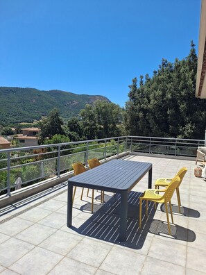 Une terrasse avec une table et des chaises, une balustrade et une vue sur une montagne.