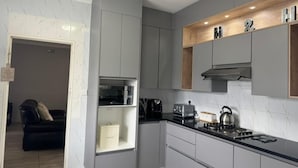 Uma cozinha moderna com armários cinza, bancada preta e forno embutido.