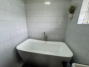 A modern bathroom with a freestanding bathtub, tiled walls, and a potted plant. - Casamaya Avondale, Harare. Newly Renovated (Harare)