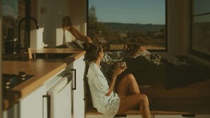 Un dormitorio acogedor con un ventanal grande, una cama y una zona de cocina con lavamanos y encimera.