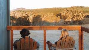 Two wooden Adirondack chairs facing a scenic view of a forested hillside. - Tiny Rosie Summary:<br>S (Mount Crawford)