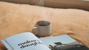 A magazine on a bed with a cup.
