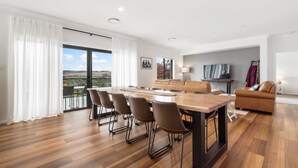 Una sala de estar moderna con comedor, sofá, televisor y vista al exterior.