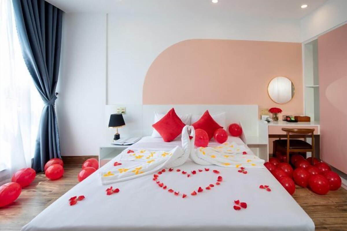 A hotel room with a bed, a desk, and a mirror.