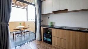 A modern kitchen with wooden cabinets, a black countertop, and a built-in mini fridge. - FIRST Studio Hotel Da Nang (Da Nang)