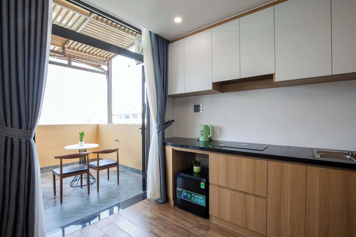 A modern kitchen with wooden cabinets, a black countertop, and a built-in mini fridge.