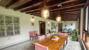 Un grand espace dédié à la salle à manger, avec une table en bois et des chaises roses, un canapé et un banc.