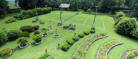 Una cancha de tenis rodeada de jardines cuidados y árboles.