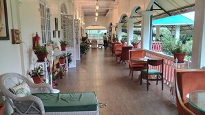 Un espace extérieur aménagé, abrité et doté de mobilier en osier et de plantes en pot.