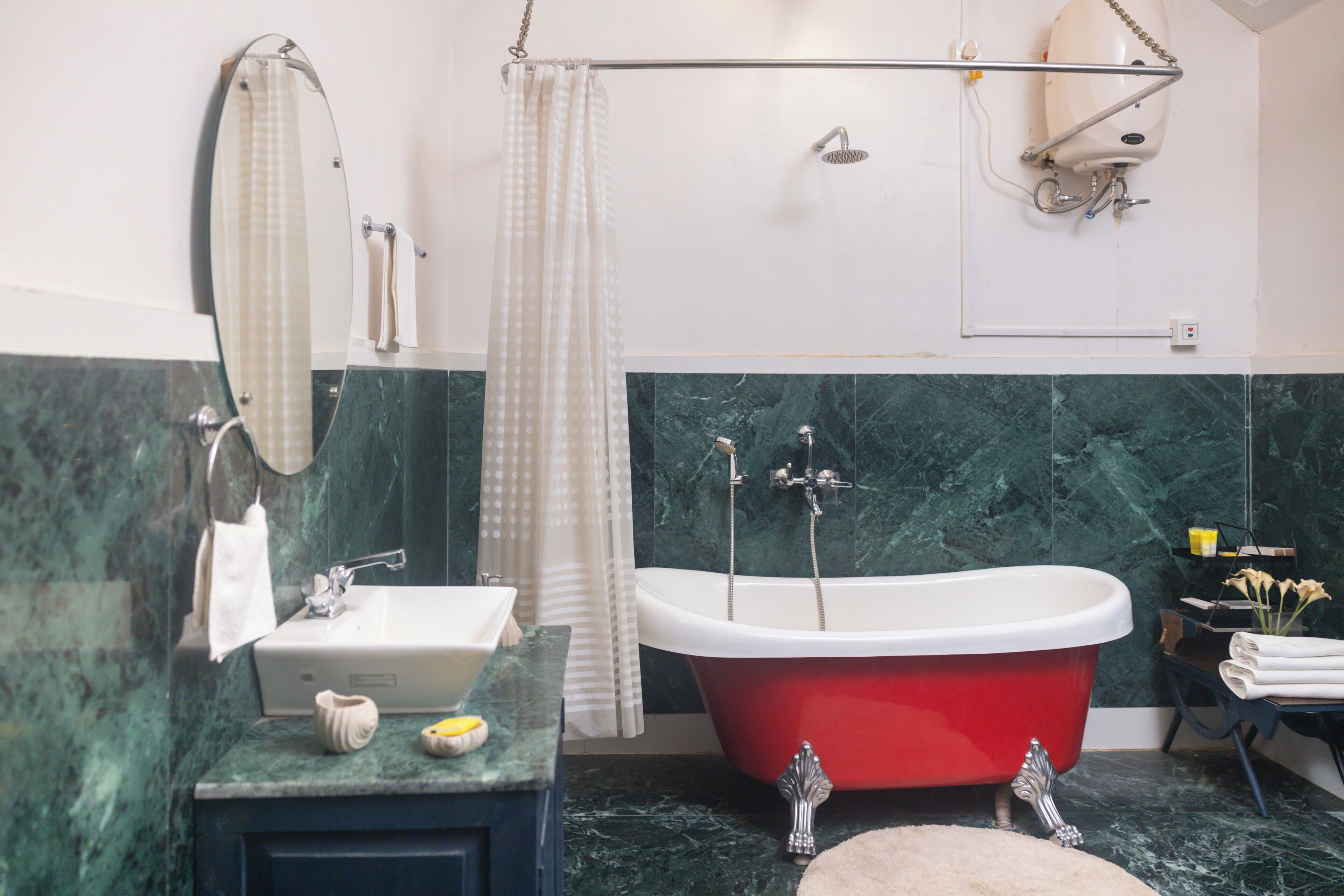 A bathroom with a red bathtub, a white sink, a mirror, and a shower area.