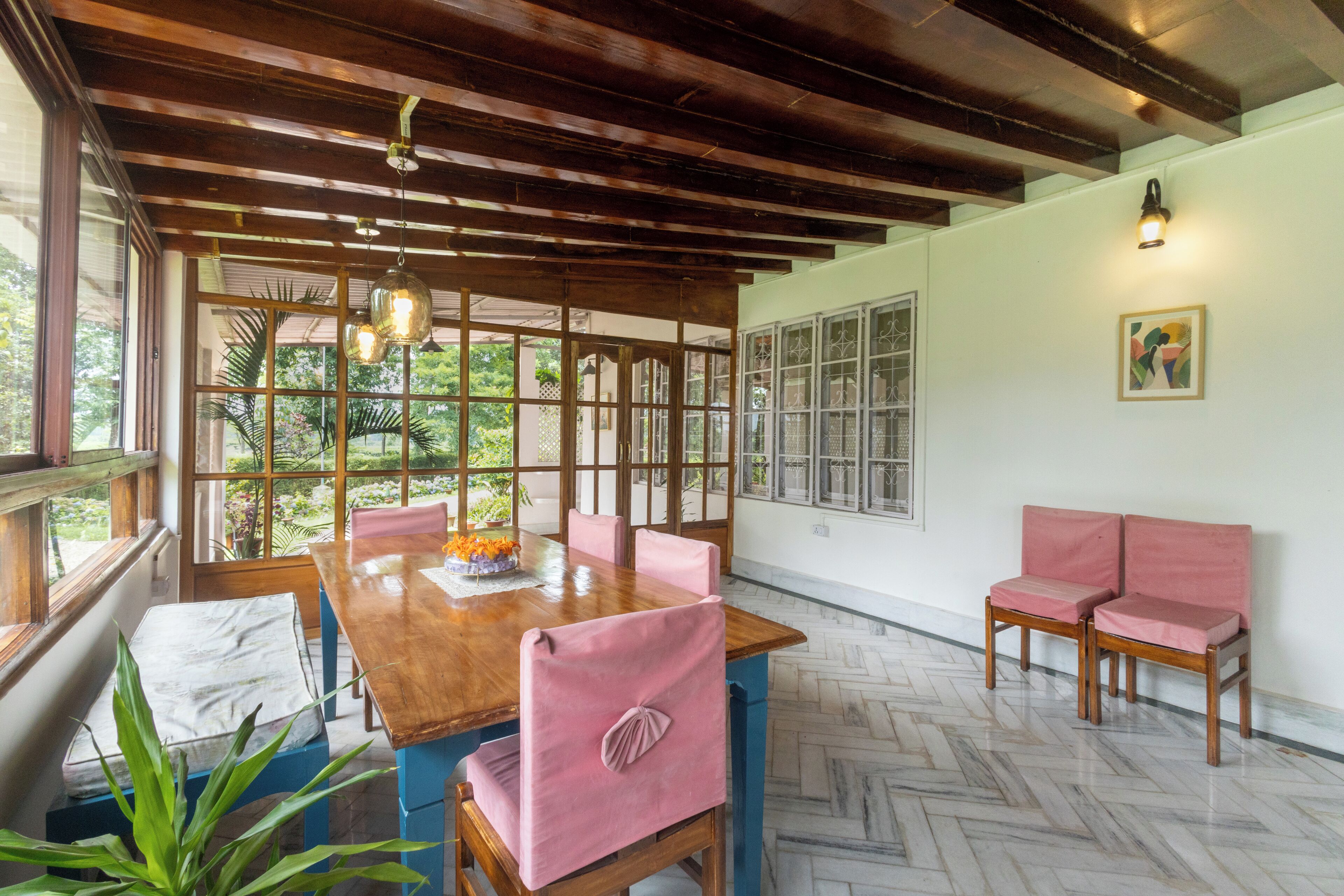 Un coin repas avec une table en bois, des chaises roses et un banc.