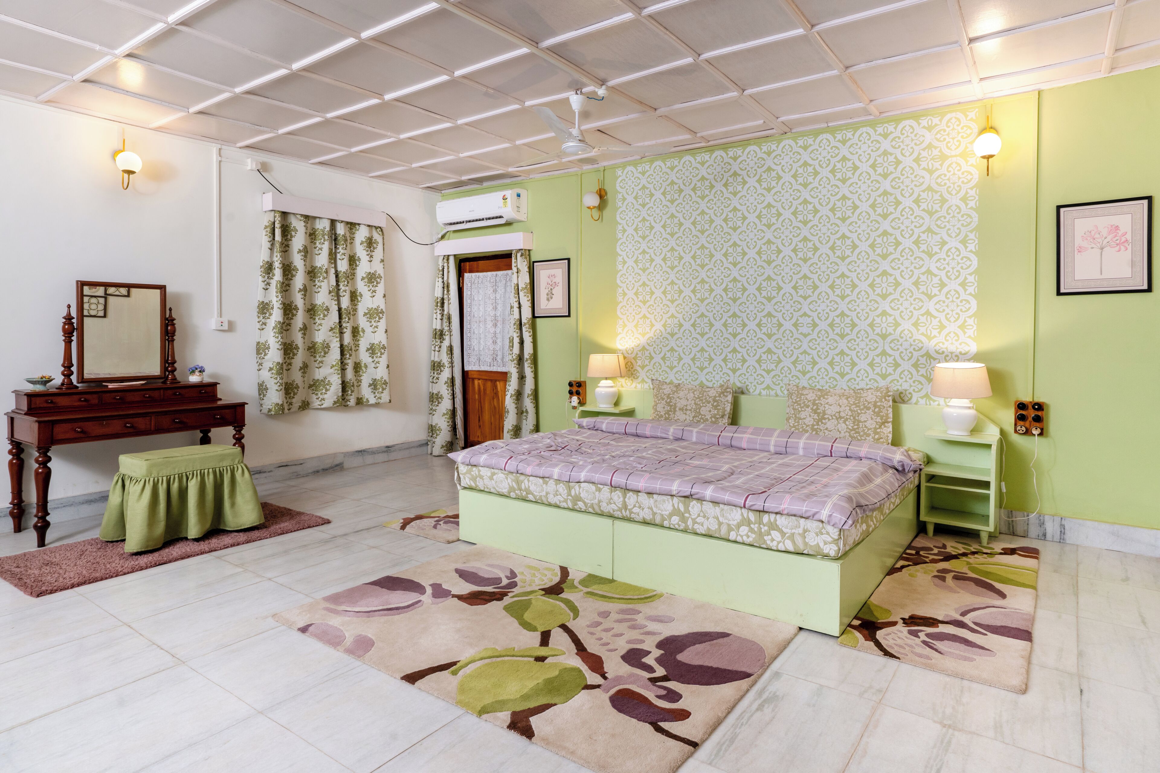 A bedroom with a bed, a dresser, a mirror, a window with curtains, and a wall with patterned wallpaper.