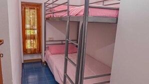 A room with bunk beds, a door, and a window with curtains. - In the Green near the Sea (Orbetello)