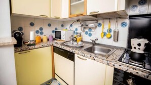 A compact kitchen with a dishwasher, a stove, and a sink. - In the Green near the Sea (Orbetello)
