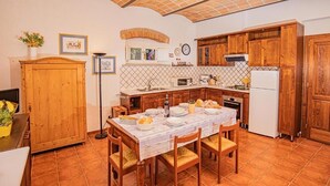 Une cuisine avec des meubles en bois, un dosseret carrelé et une table à manger pour quatre personnes.