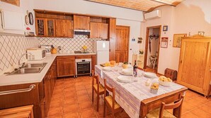 Une cuisine compacte avec des meubles en bois, un pare-feu en carreaux et une table à manger pour quatre personnes.