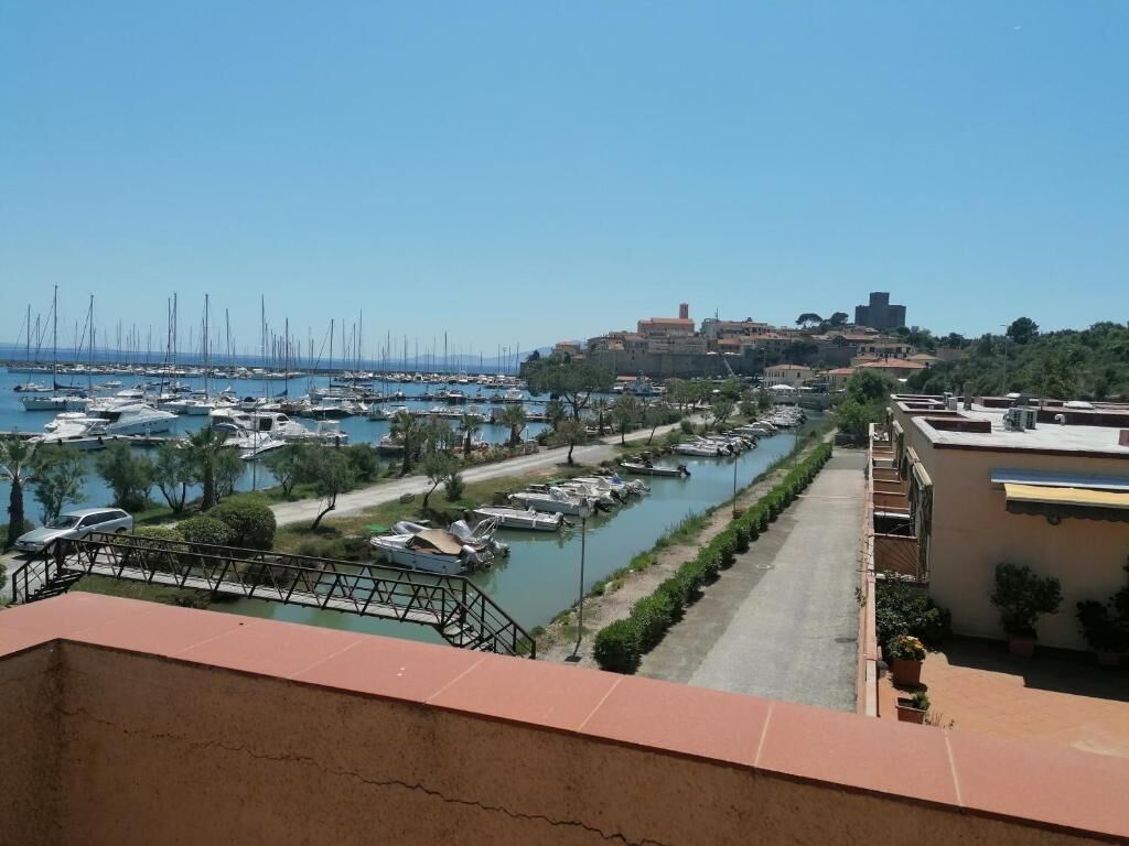 Un port de plaisance avec des bateaux, un ciel dégagé et un bâtiment historique en arrière-plan.