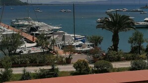A marina with boats docked, surrounded by greenery and a clear sky. - View of the harbour (Orbetello)