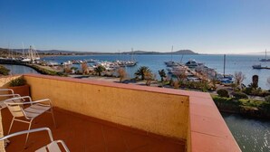 A balcony with chairs overlooking a marina with boats and a clear sky. - View of the harbour (Orbetello)