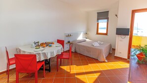 A compact room with a dining table, red chairs, a bed, and a television. - View of the harbour (Orbetello)