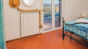 A room with a bed, a radiator, a window with a view, and a door. - The View of Talamone (Orbetello)
