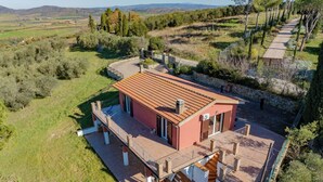 A modern house with a red roof, a covered patio, and a stone wall. - The View of Talamone (Orbetello)