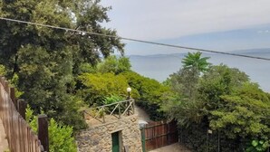Vista de una zona costera con un edificio de piedra, una valla de madera y abundante vegetación.