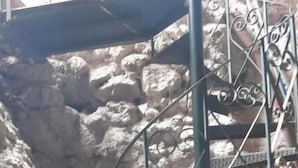 Una escalera de caracol con barandillas de metal ornamentadas sobre un fondo de pared de piedra.