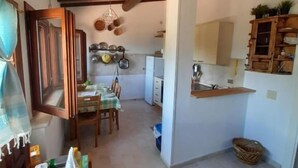 Una cocina compacta con comedor, vigas de madera en el techo y una pequeña mesa de comedor con sillas.