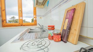 A kitchen with a window, a sink, a wooden cutting board, and jars of spaghetti sauce. - The sea is close at hand. (Orbetello)
