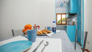 A dining area with a table set for two, featuring a plate of cookies, a blue mug, and a water bottle. - The sea is close at hand. (Orbetello)