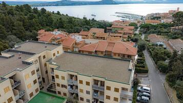 Una cittadina costiera con edifici a tetti in terracotta, un porto turistico e vista sul mare.