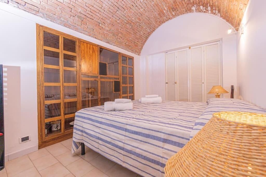 A bedroom with a large bed, a wooden wardrobe, and a brick ceiling.