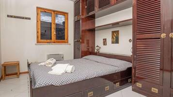 Una camera da letto con un letto, un'armadietto in legno, una finestra e un comodino.