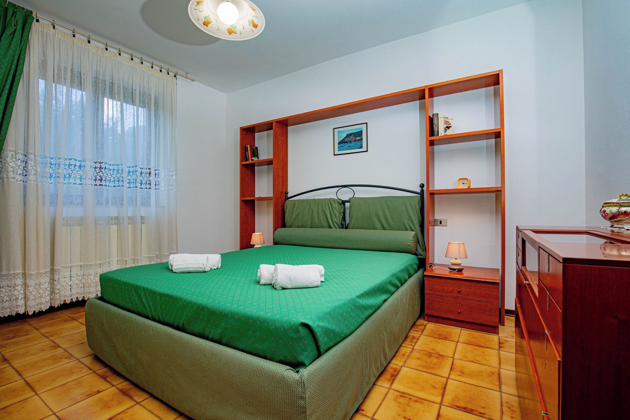 Une chambre à coucher comprenant un lit, une table de chevet, une commode et une étagère.